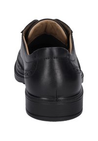 Zwarte leren dress shoe met een gladde afwerking, ronde neus, brogue-details en een gevoerde binnenkant, met een lage hak en stevige zool.