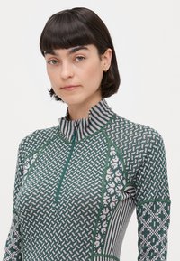 Langermet zip-up genser i grønn med geometriske mønstre, stripete krage og teksturert stoff for en tettsittende silhuett.