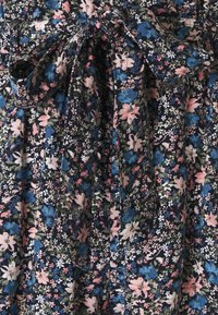 Květinové šaty z látky s tmavě námořnickým pozadím a růžovými, modrými a bílými květy; obsahují detail mašle v pase.