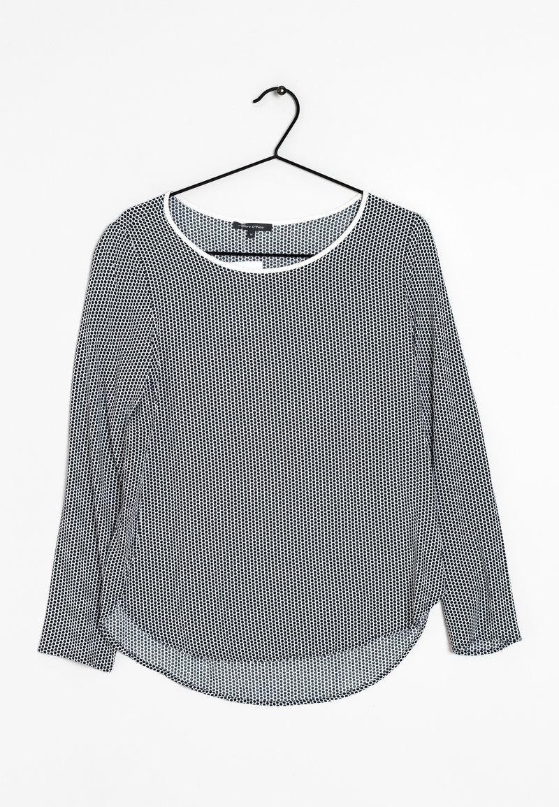 Blouse à manches longues avec un motif à pois noir et blanc, dotée d'un col rond et d'un ourlet arrondi. Fabriquée en tissu léger et transparent.