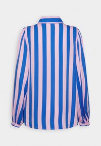 La chemise à manches longues présente des rayures verticales roses et bleues, un col classique et des poignets élastiques en tissu texturé.