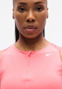 Ροζ αθλητικό τοπ με φερμουάρ, με στρογγυλή λαιμόκοψη και λογότυπο Nike σε λευκό. Ομαλή υφή και εφαρμοστή σχεδίαση.