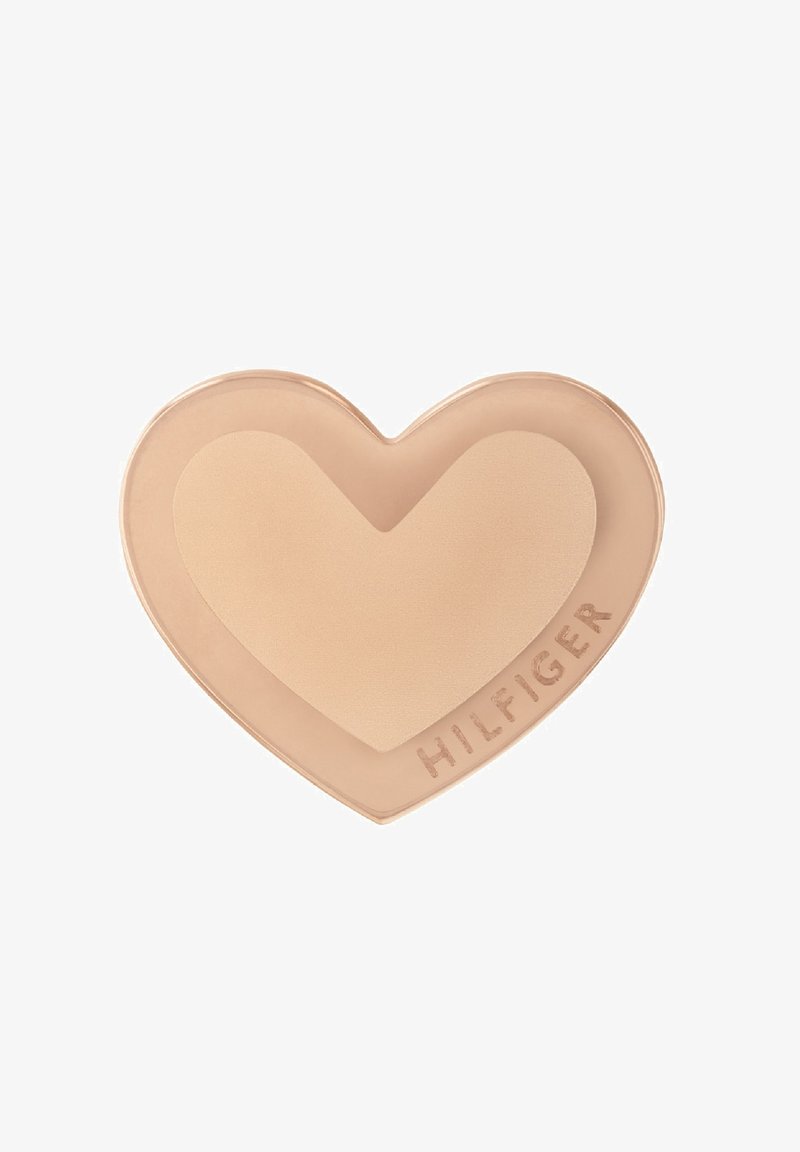 Prodotto cremoso a forma di cuore di colore beige chiaro, con una consistenza liscia. Logo "HILFIGER" stampato di lato con una finitura in contrasto.
