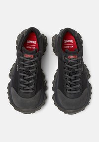Czarne sneakersy z teksturowaną podeszwą, z szarymi i czerwonymi elementami, grubymi sznurowadłami oraz logo "Camper" i "GORE-TEX" na języku.