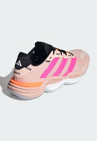 Ružová a čierna športová obuv s tromi výraznými ružovými pruhmi, textúrovaným sieťovaným zvrškom, oranžovými akcentmi a odpruženou bielou podrážkou.