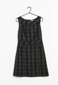 Mörkgrå ärmlös klänning med bred halsringning, rutmönster, knappade flikfickor i midjan, hängande på svart galge mot vit bakgrund.