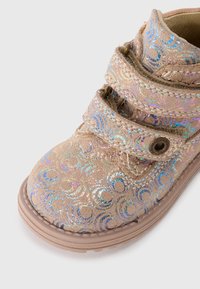 Rosa suede ankelstøvler med iriserende cirkulære mønstre, to Velcro-remmer og en rund tå. Gummisål med tekstureret greb.