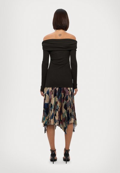 Off-the-shoulder svart langermet topp kombinert med en plisserte, flerfarget midi skjørt som har nyanser av blått, burgunder og krem.