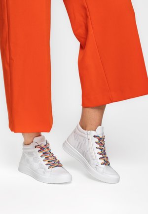 White high-top sneakers featuring perforated sides, multicolored laces, and a side zipper. Paired with orange wide-leg trousers.