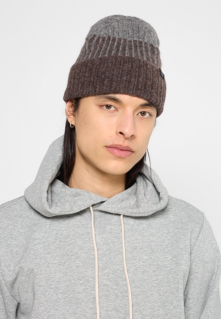 Dzianinowa czapka w kolorze szarym i brązowym, z prążkowaną fakturą i złożonym projektem. Połączona z szarym kapturem.