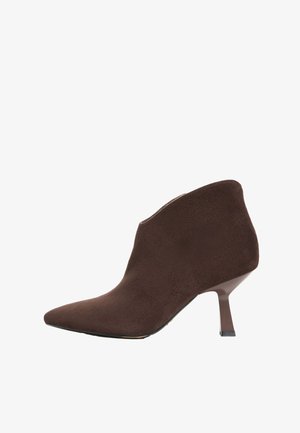 Bruine suède enkellaars met een puntige neus en een slanke hak van gemiddelde hoogte, zijaanzicht op witte achtergrond.