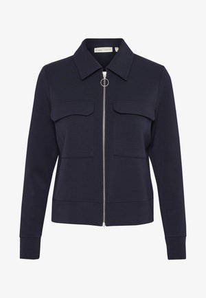 Veste zippée marine en tissu doux avec un col, deux poches avant et un zip circulaire. Texturé lisse et coupe ajustée.