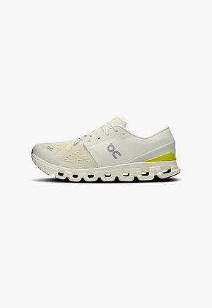 Running shoe in light beige with a textured mesh upper, yellow accents, and a cushioned sole featuring cloud-like segments for support.