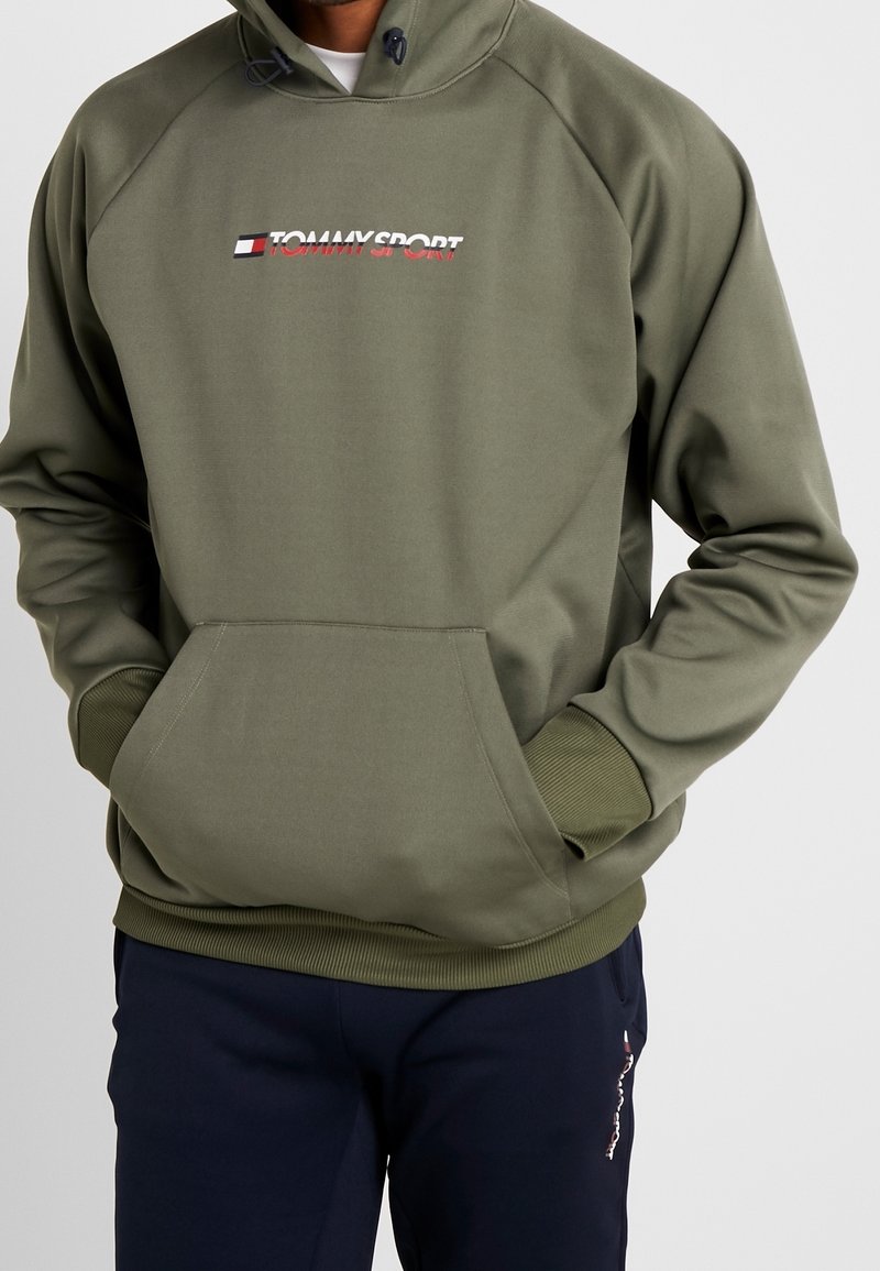 Felpa verde oliva con tasca frontale, cappuccio regolabile con coulisse e logo "TOMMY SPORT" ricamato. Presenta polsini e orlo a costine.