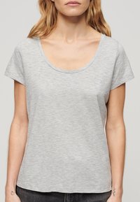T-shirt gris à manches courtes avec un col rond, fabriqué en tissu léger et doux, arborant un logo discret sur la poitrine.