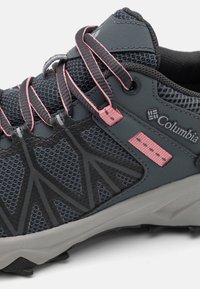 Chaussure de randonnée Columbia gris foncé avec des lacets accentués de rose, tissu en maille et semelle résistante pour les activités de plein air.