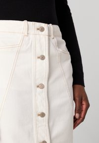Witte denim rok met een hoge taille, voorzien van een knoopsluiting aan de voorkant, contrasterende stiksels en zijzakken. Glide textuur, strakke ontwerp.