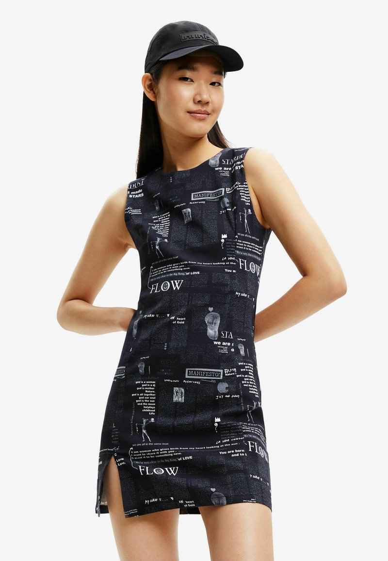 Robe noire sans manches avec un imprimé en blanc et gris. Le côté présente une fente. Associée à une casquette noire assortie.