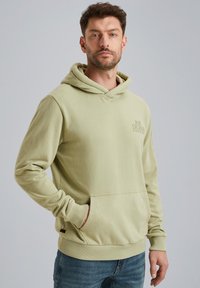 Felpa verde chiaro in tessuto morbido, con tasca a marsupio e polsini a costine. Dettaglio del logo minimale sul petto.