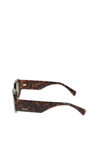 Καφέ γυαλιά ηλίου με σχέδιο χελώνας και υπερμεγέθη τετράγωνα φακούς. Διαθέτουν κομψό σκελετό με γυαλιστερό φινίρισμα και χρυσή επωνυμία στο πλαϊνό μέρος.