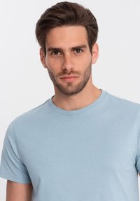 Lyseblå T-shirt med rund hals fremstillet af blødt stof, med kortærmer og en glat overflade, designet til afslappet brug.
