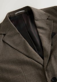 Brown houndstooth patterned suit jacket with a black interior lining, peaked lapels, and a single-button closure.