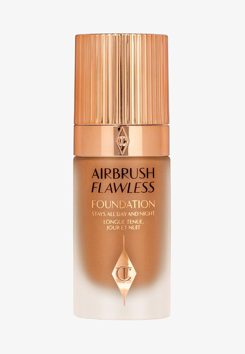 Airbrush Flawless Foundation in a frosted glass bottle with a gold ribbed cap. Label features black and gold text on a bronze background.