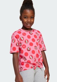 T-shirt rosa a maniche corte con grandi pois rossi e grafiche di Minnie Mouse. Il dettaglio dell'orlo annodato aggiunge texture. Materiale in cotone morbido.