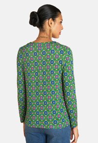 Grünes Langarmshirt mit einem lebhaften Blumenmuster in Blau und Pink, aus weichem Stoff gefertigt, mit rundem Halsausschnitt und lockerer Passform.