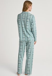 Lichtblauwe, gestreepte pyjamastelletje met een gekraagde top en rechte pijpen, versierd met ingewikkelde bloem- en geometrische patronen. Katoenen materiaal.