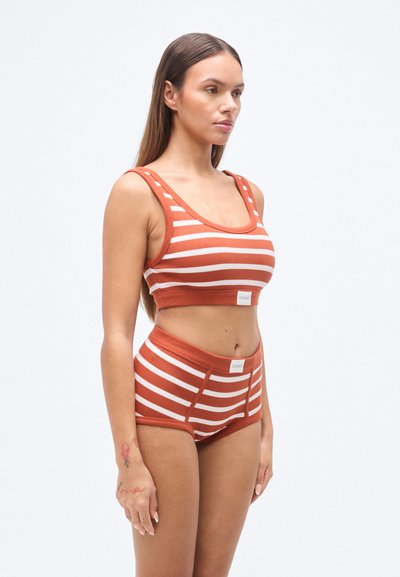 Ριγέ crop top και σλιπ με ψηλή μέση σε αποχρώσεις σκουριάς και κρέμας. Ριμπ υφή με φαρδιές τιράντες και λεπτομέρεια με λογότυπο στη ζώνη μέσης.