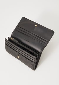 Melns ādas maks ar gludu un teksturētu virsmu. Aprīkots ar vairākām karšu kabatām, ar rāvējslēdzēju aizdari un zelta pogu slēgšanu.