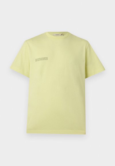 Ανοιχτό κίτρινο βαμβακερό T-shirt με κοντά μανίκια, μικρό μαύρο κείμενο στο αριστερό στήθος και στρογγυλή λαιμόκοψη.