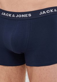Donje hlače morske plave boje od pamuka, s mekanim elastičnim pojasom na kojem je u bijelom otisnuta oznaka "JACK & JONES". Vidljivi detalji šivanja.