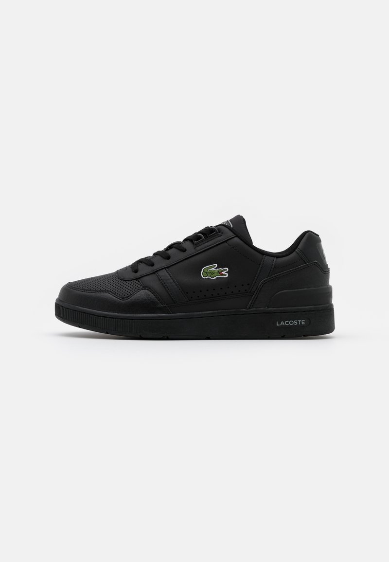 Baskets basses noires Lacoste avec lacets, détails perforés et logo crocodile vert sur le côté.