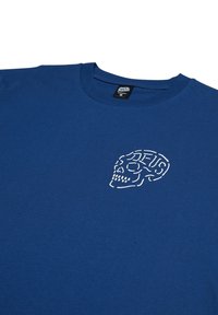 Blue cotton t-shirt featuring a white skull graphic embroidered on the left chest. Rounded neckline and short sleeves.