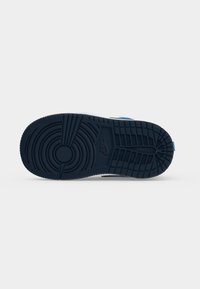 Μαύρη σόλα αθλητικού παπουτσιού Nike με κυκλικά και ορθογώνια σχέδια πέλματος σε απλό γκρι φόντο.