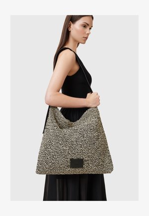 Sac à épaule tissé noir et blanc avec une forme décontractée, de grande taille, et un panneau d'accent en cuir noir lisse à l'avant.