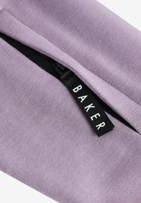 Violetinis audinys su lygia tekstūra turi juodą užtrauktuką ir etiketę su užrašu "BAKER" balta spalva, esančią šalia užtrauktuko atidarymo.