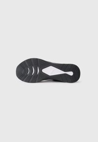 Sole de cauciuc alb și negru a unei încălțăminte Puma cu modele de aderență și logo-ul Puma în centru.