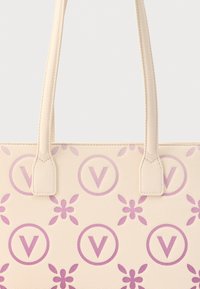 Bež ročna torbica z dvema naramnicama, z vzorcem ponavljajočih se vijoličnih črk "V" v krogih in cvetličnimi motivi.
