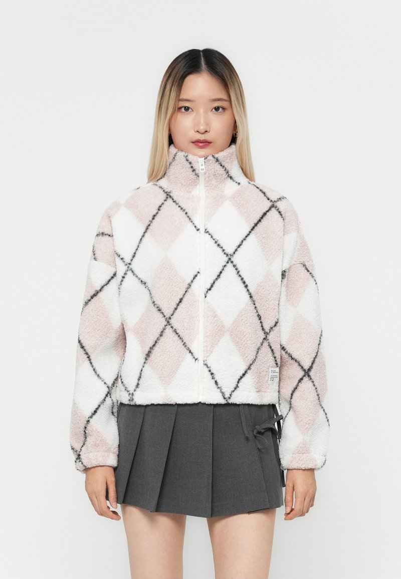 Fleecejakke med rosa, hvit og svart argyle-mønster; har høy krage og frontglidelås; myk tekstur, kort design.