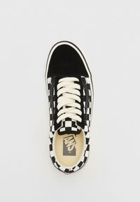 Baskets Vans à carreaux noirs et blancs avec des lacets blancs et un capuchon en daim noir, vues de dessus sur un fond blanc.