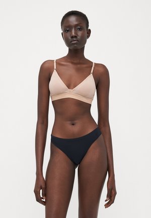 Svijetlosmeđi bralette s tankim naramenicama i V-izrezom uparen s crnim bikinijem s visokim strukom. Glatka tkanina, minimalni šavovi.