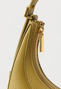 Groene leren handtas met een gestructureerde afwerking, gebogen ontwerp, rits in goudkleur en een merkembleem. Heeft gestikte accenten bij de naden.