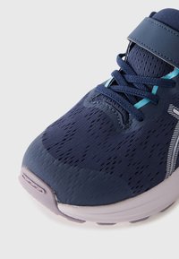 Navy athletic shoe with mesh upper, light blue accents, and a textured toe cap. Features laces and a hook-and-loop strap for secure fit.
