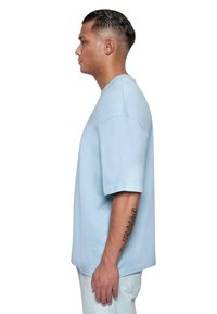 Lyseblå bomulds t-shirt med afslappet pasform, korte ærmer og rund halsudskæring. Glat tekstur, minimal detaljering og lige snit.