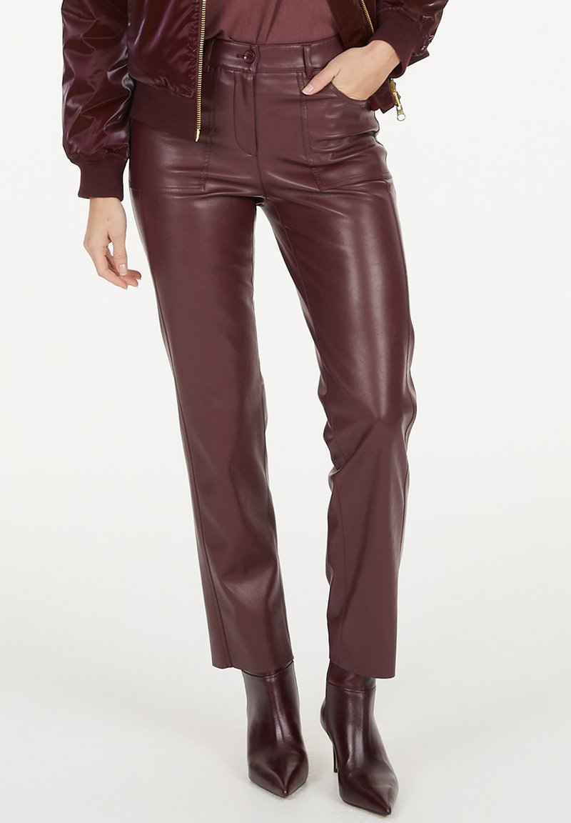 Burgunderfarbene Lederhosen mit schmalem Schnitt, hoher Taille und minimalen Nähten. Kombiniert mit passenden spitzen Ankle Boots für einen harmonischen Look.