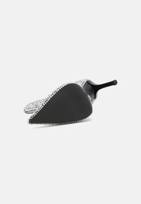 Chaussure à talon haut argentée ornée, avec un bout pointu, une semelle noire texturée et des accents en strass brillants le long du bord.