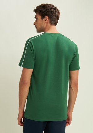T-shirt verde a maniche corte realizzato in cotone, con dettagli bianchi lungo le spalle e un collo a giro. Texture liscia.